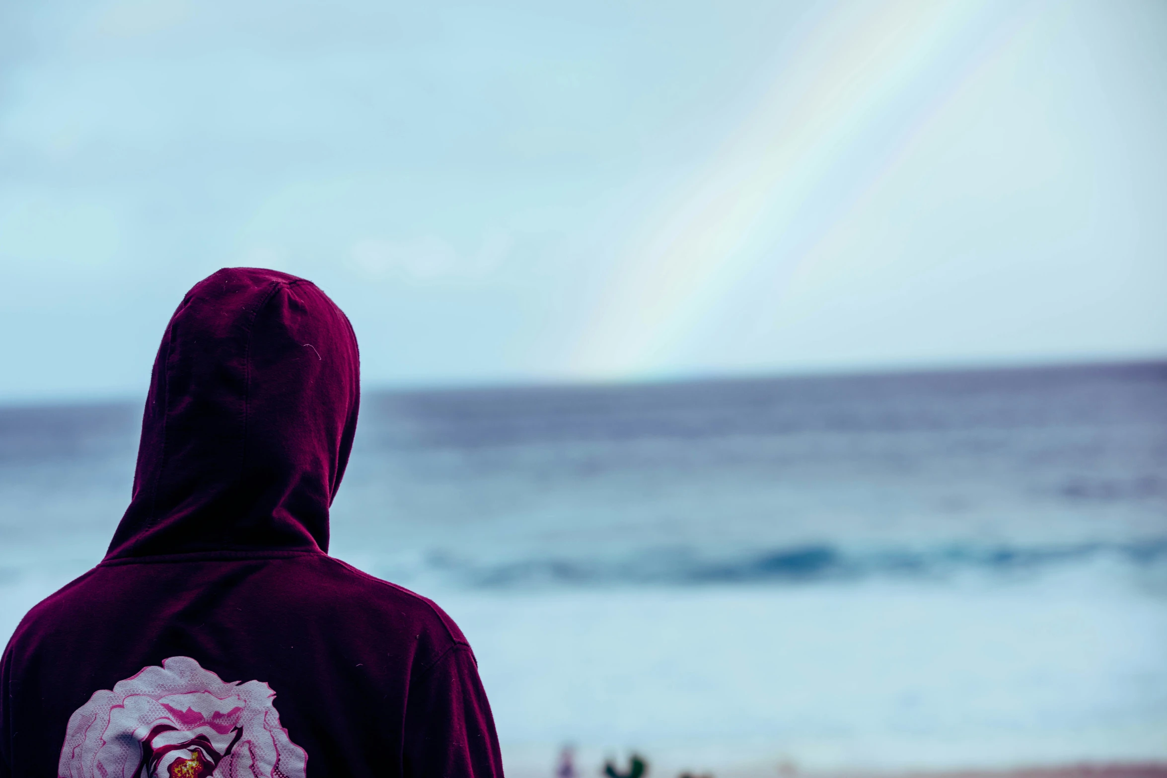 a person in hoodie with the ocean in the background