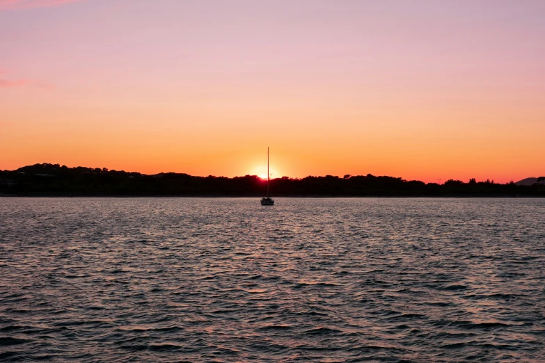 sunset over a body of water with a boat on the water