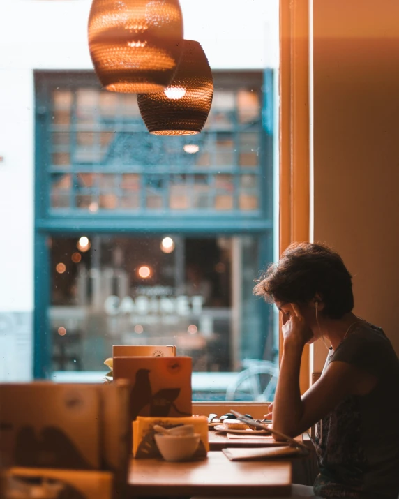 the woman is working on her laptop in front of a window