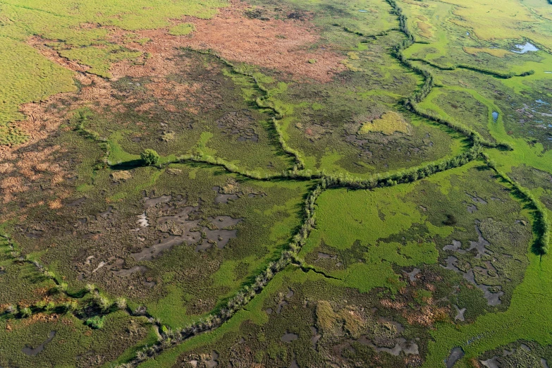 a river cuts through the green grass that surrounds this area