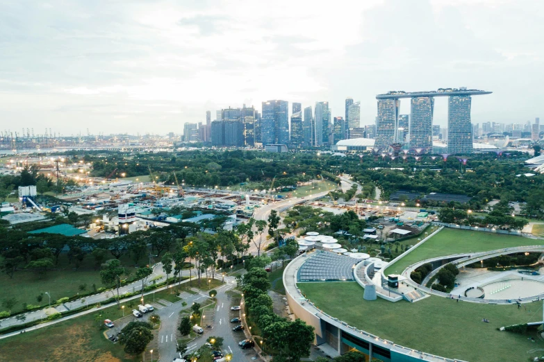 a city filled with tall buildings next to a lush green field