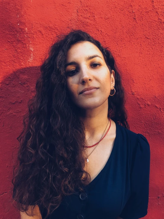 there is a woman that is standing in front of a red wall