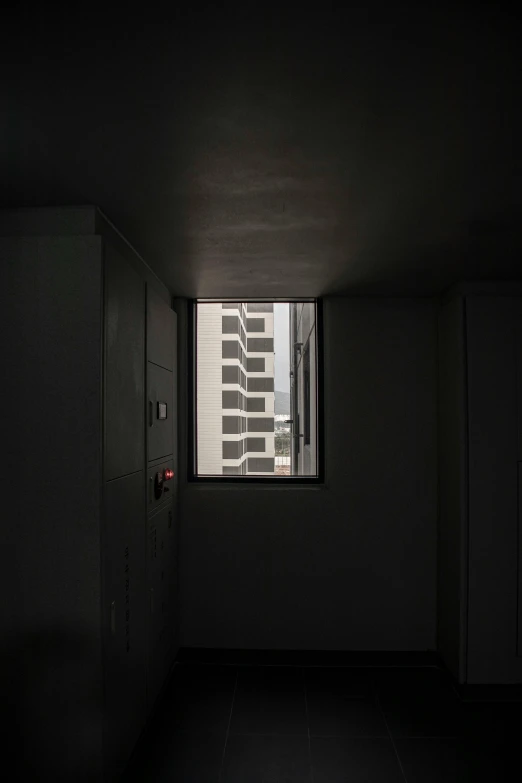 the room is dark and has a window looking out at city buildings