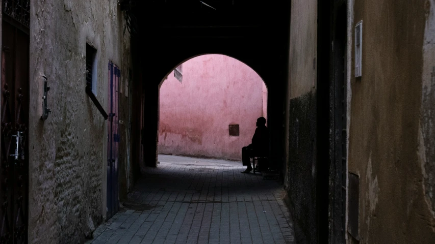 a dark alley way, with a woman sitting in the middle