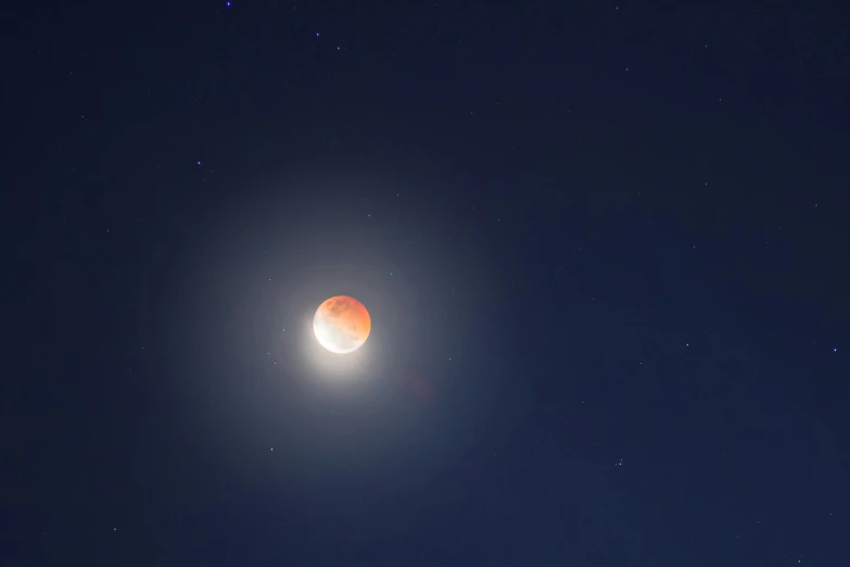 a bright orange moon shines against the night sky