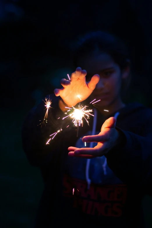 a young man holds sparklers as he stands in the dark