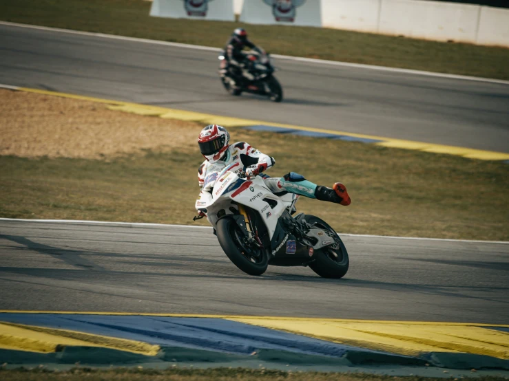 two people riding motorcycles on a track during the day