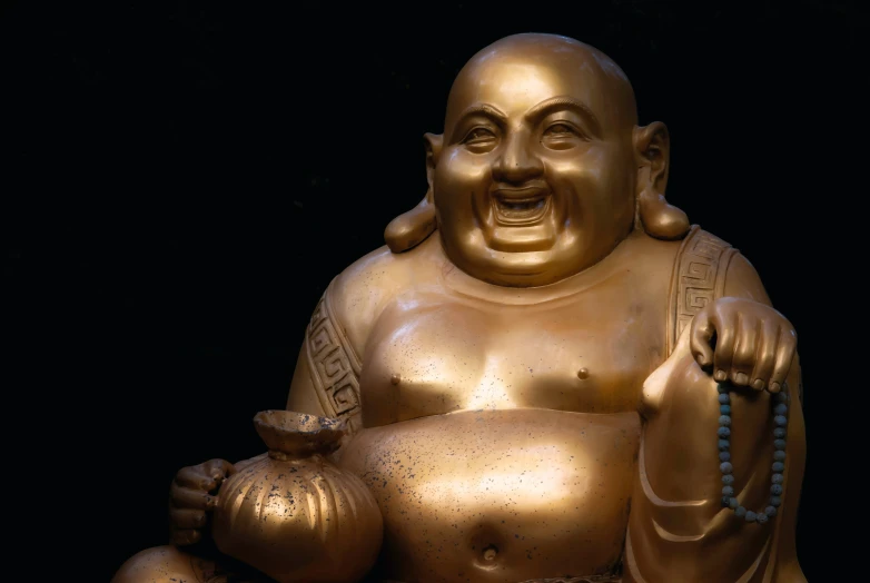 a gold statue that has an iron teapot in it