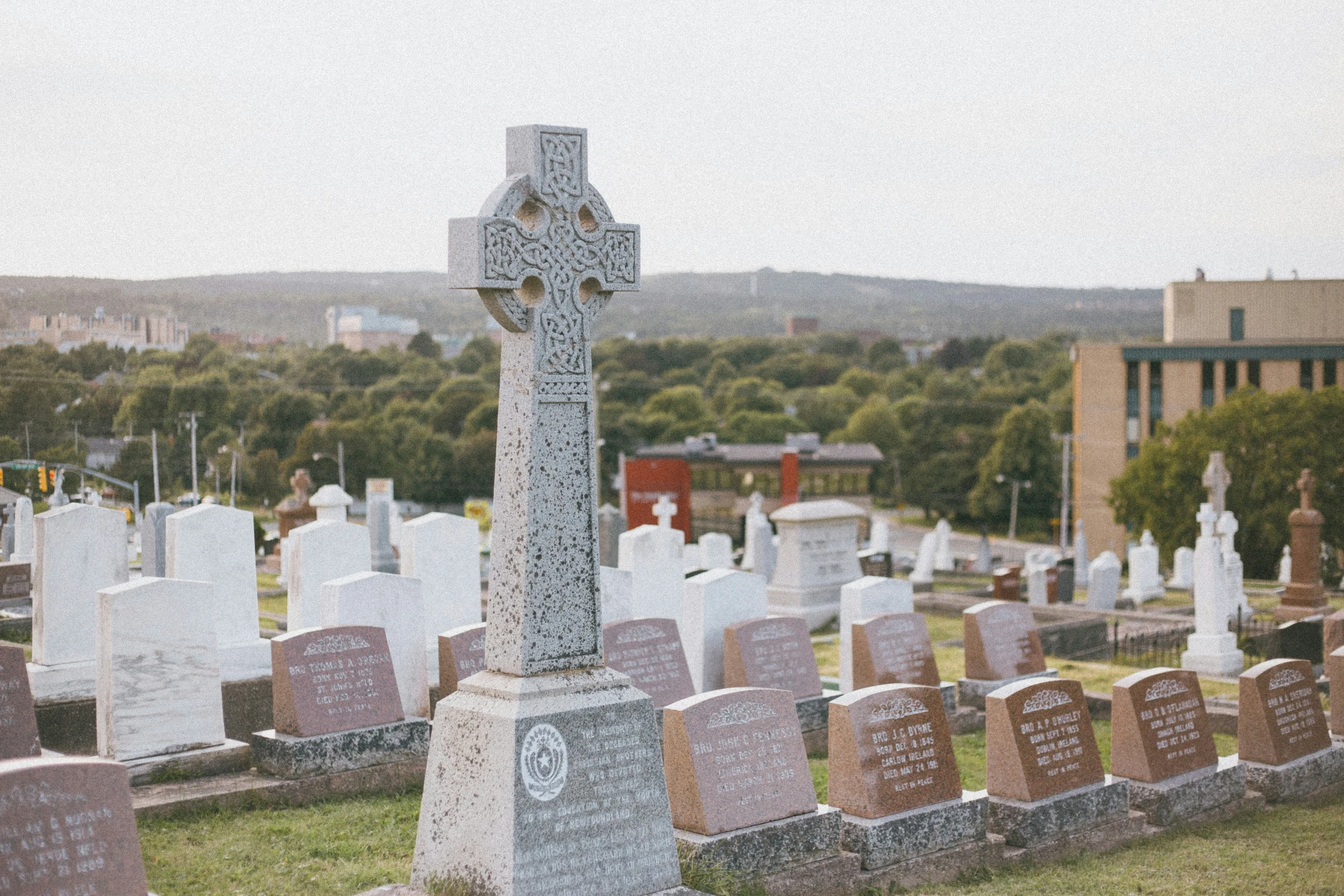 a cross sitting at the end of a cemetery