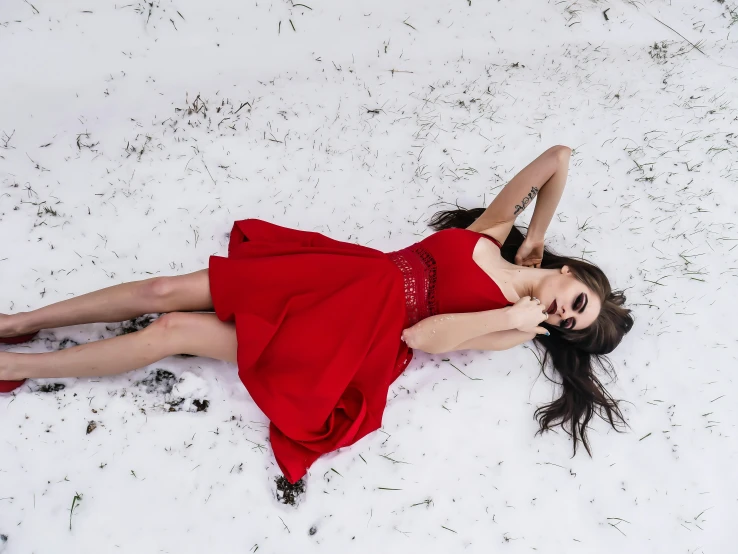 woman laying on snow with red dress on