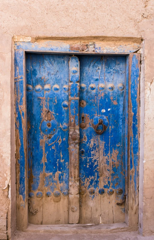 the old, worn door is blue with brown stripes