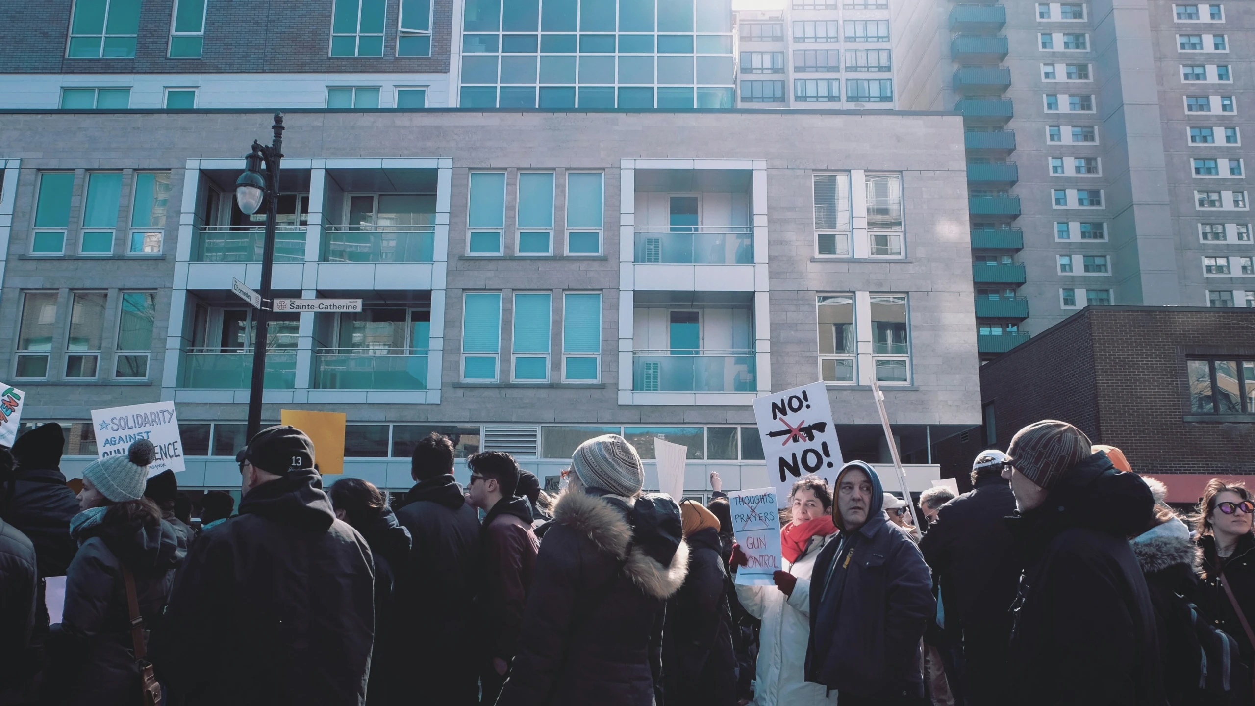 several people are standing outside holding signs and wearing winter gear