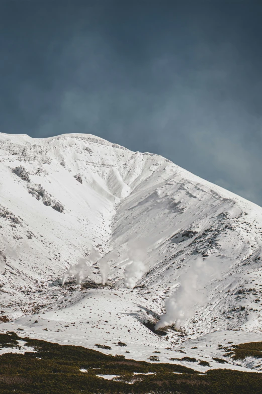 a distant mountain covered in snow under a cloudy sky