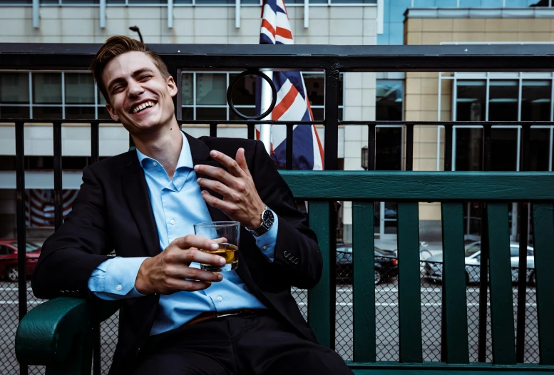 man in business suit smiling at camera on bench