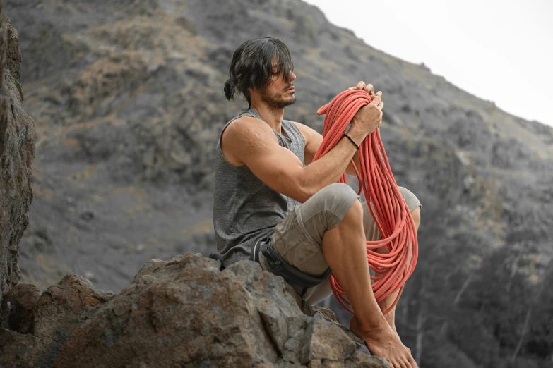 the man is holding a rope on top of a rock