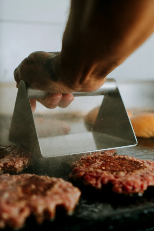 a person is removing hamburger patties from the grill