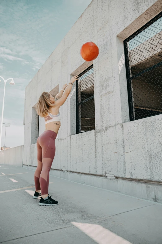 woman in athletic clothing and hat tossing a ball