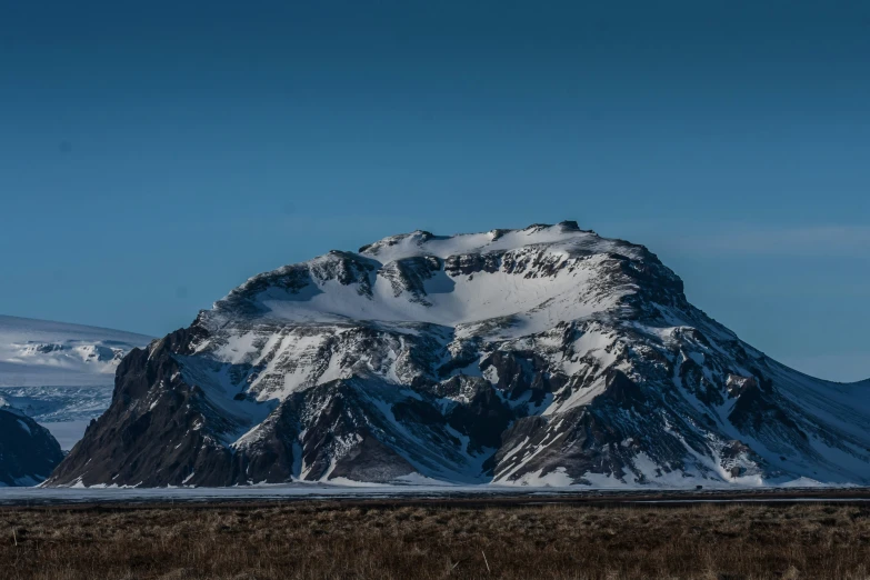 an extremely large mountain covered in snow in the middle of winter