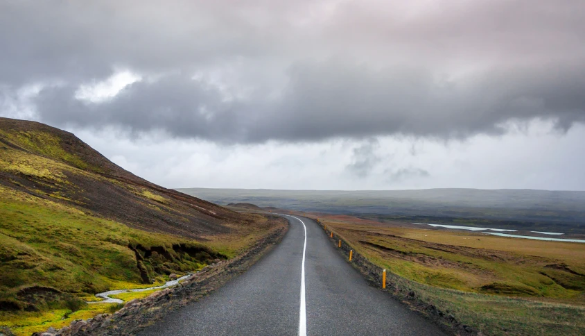 a road with cloudy skies above it on the side