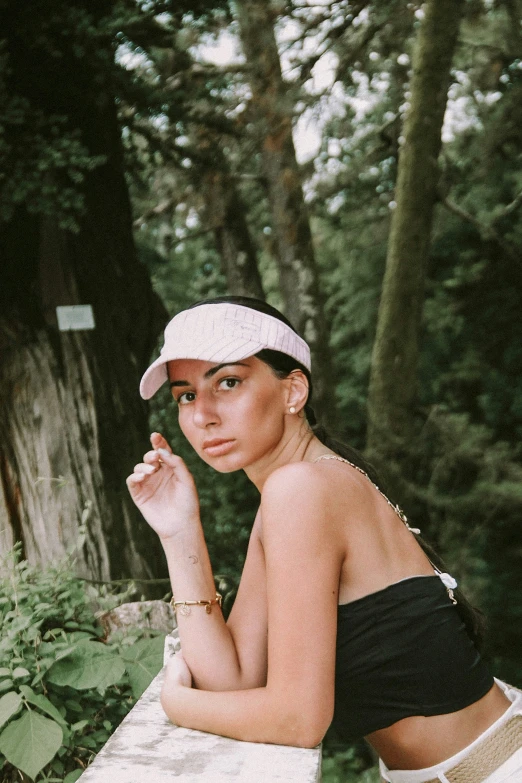 a woman sitting on a cement wall in a forest