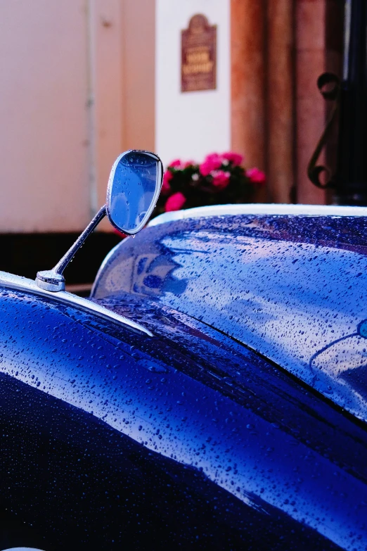 a close up of a blue car with rain on it