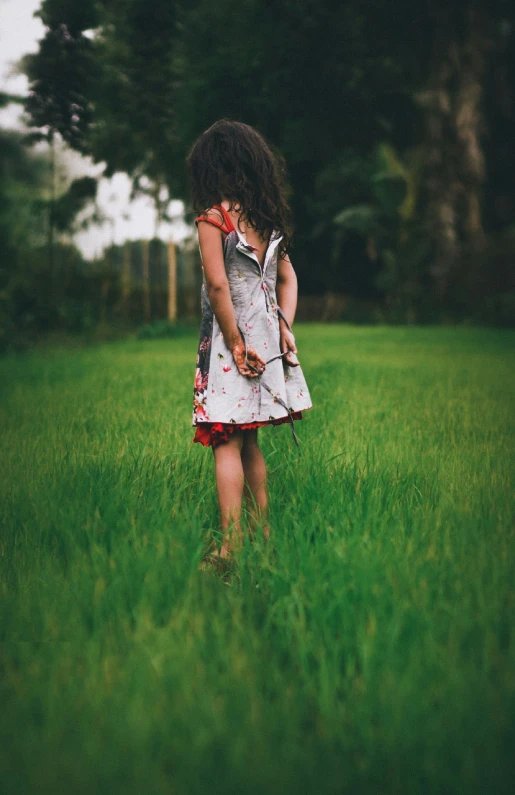 a little girl standing in a grassy field