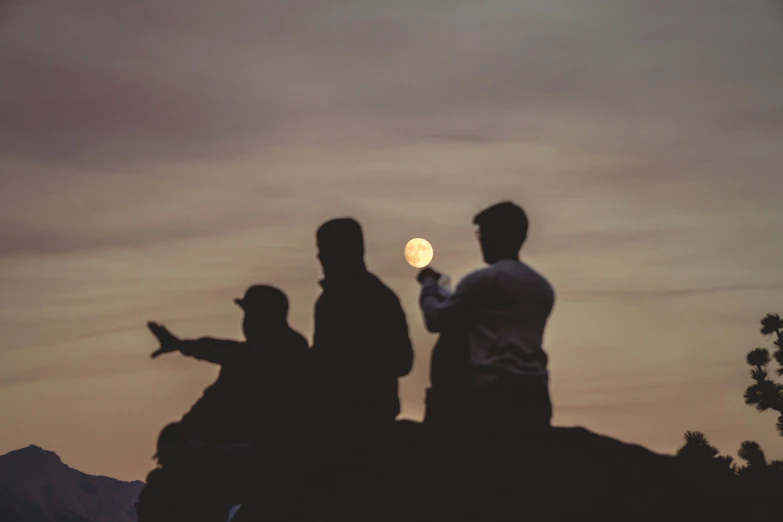 three people standing on top of a mountain and holding soing in their hands