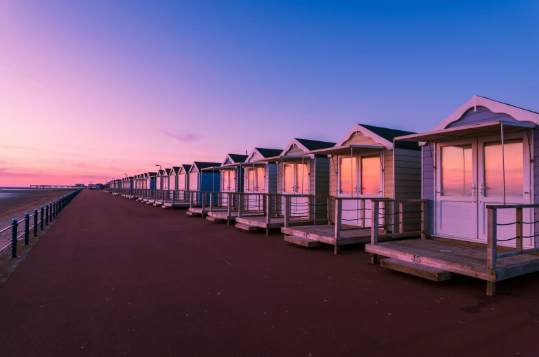 a row of houses next to the beach at sunset