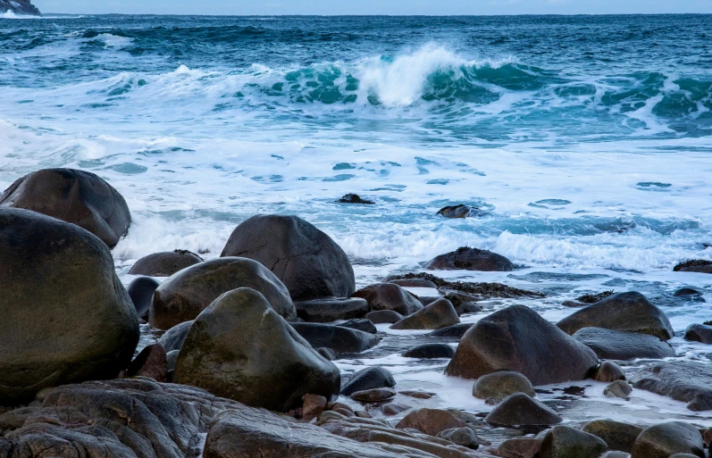 ocean waves crash onto rocks at the shore