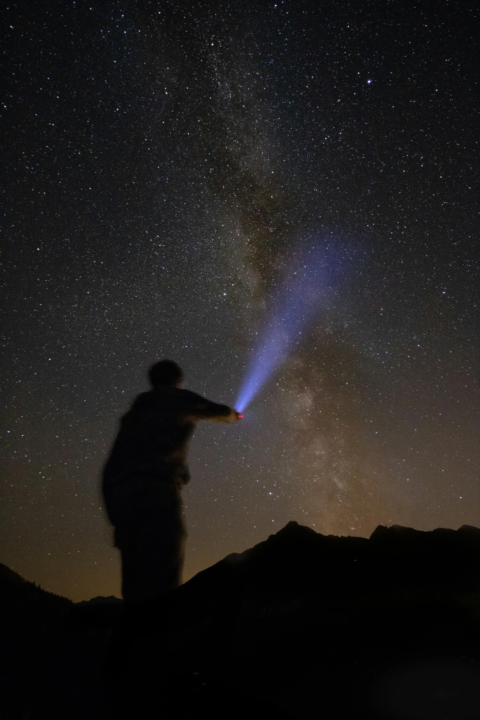 a silhouette of a man with a bright light shining on the sky