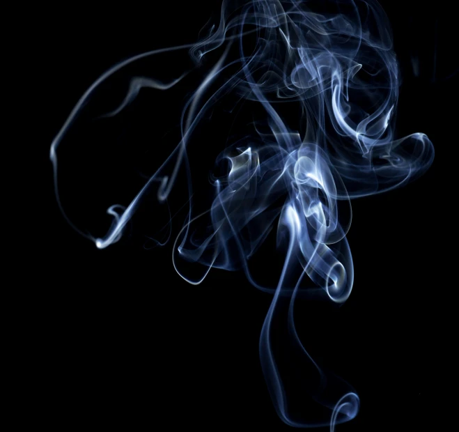 smoke swirls in the dark as it breaks apart