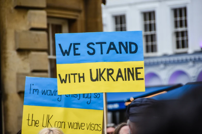 a sign is displayed in a protest with yellow and blue signs