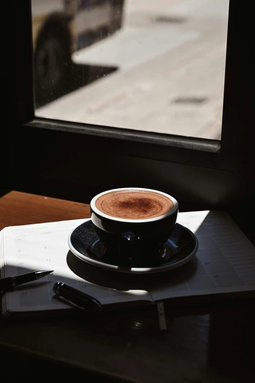 there is a cup of coffee sitting on a plate next to a window