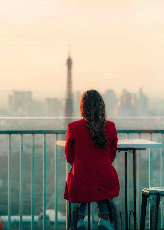 a woman is looking out over the city and trees