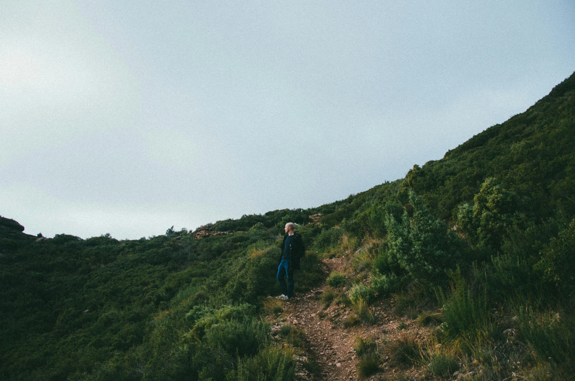 man walking up a small grassy hill