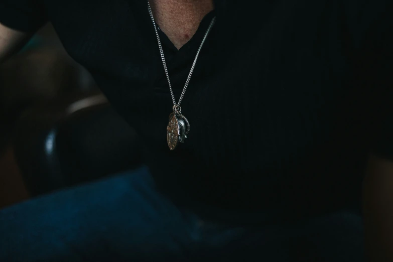 a man wearing a black shirt has a chain around his neck