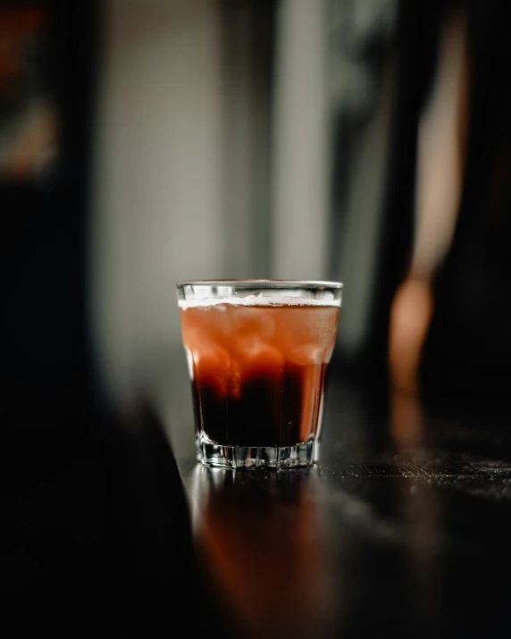 a s glass with a red liquid sits on a table