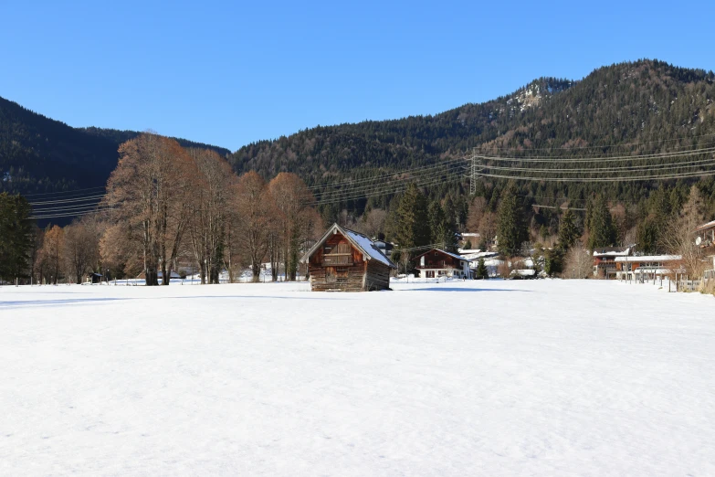 snow covered field near houses and trees near mountains