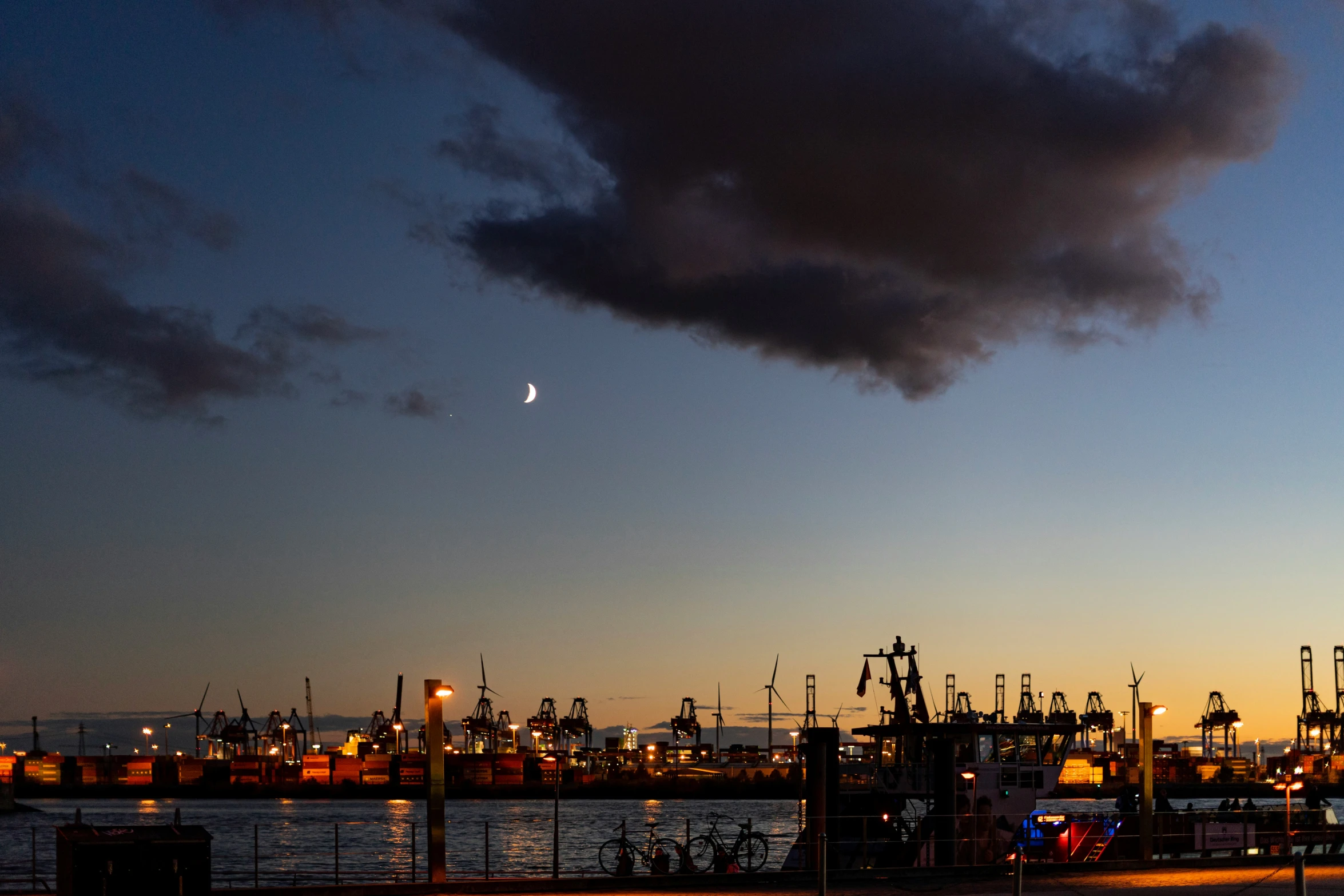 a factory building sitting next to the ocean under a dark sky