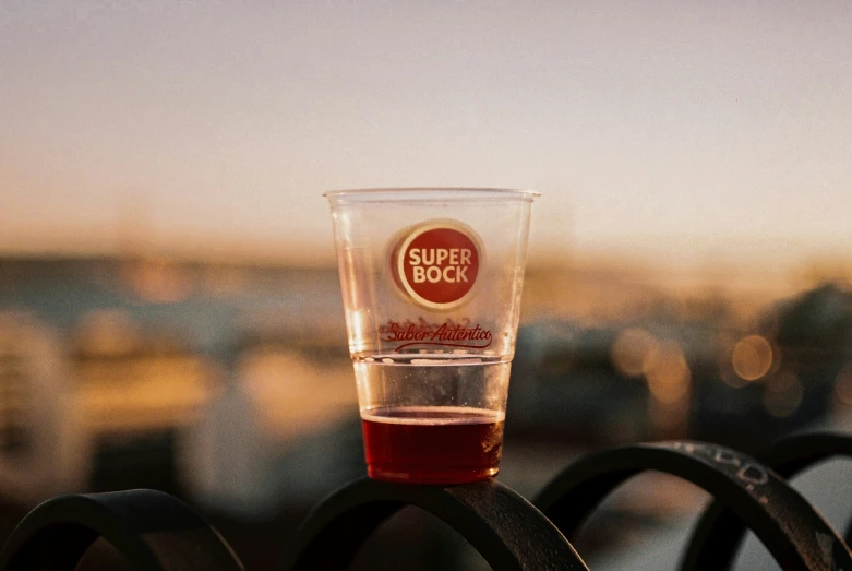 a cup with a red liquid on top is sitting on a bench