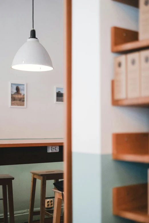 a lamp and two stools with pos on the wall