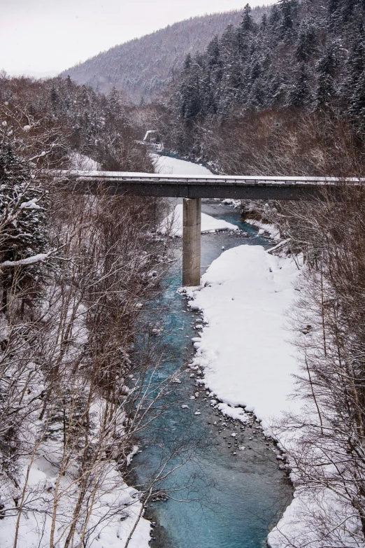 a snowy mountain is shown with a small bridge above it