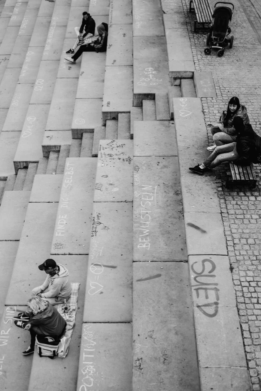 a group of people sit outside while writing on a sidewalk