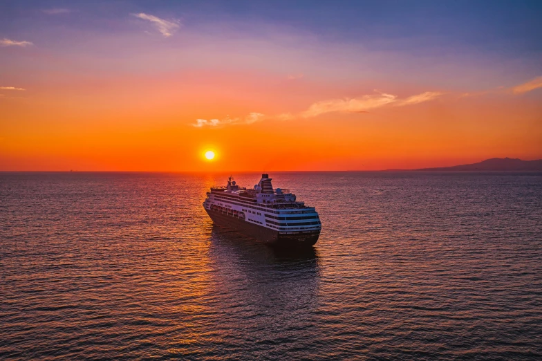 a cruise ship at sunset as it sails into the ocean