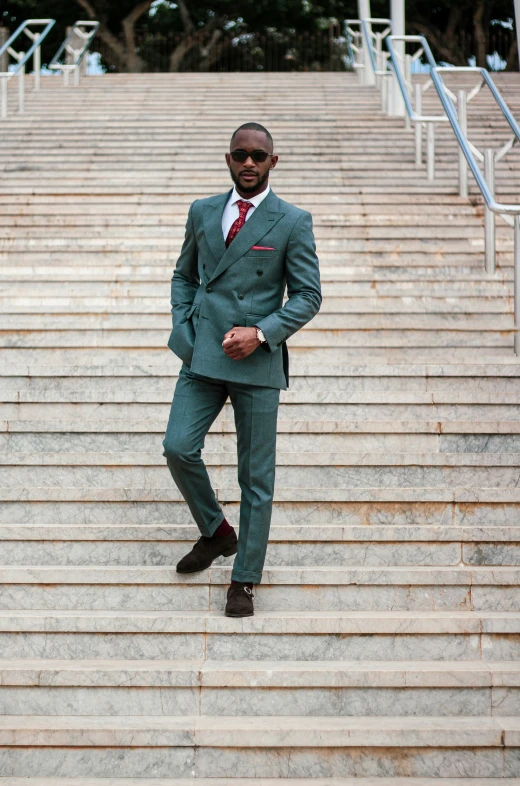 a man in a green suit posing on stairs