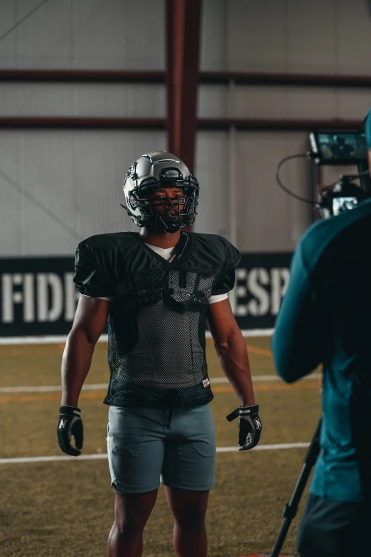 a football player standing on a field wearing a catchers gear