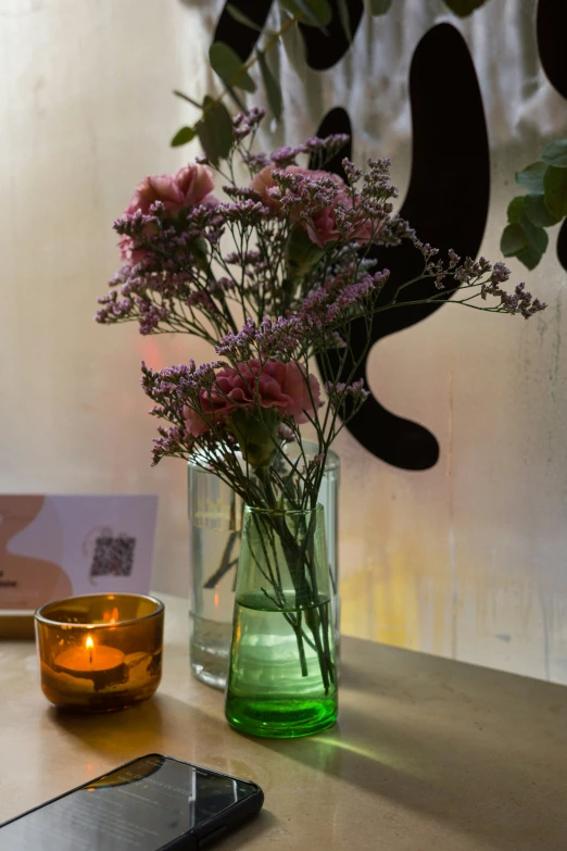 an iphone sits on the table with flowers in a vase