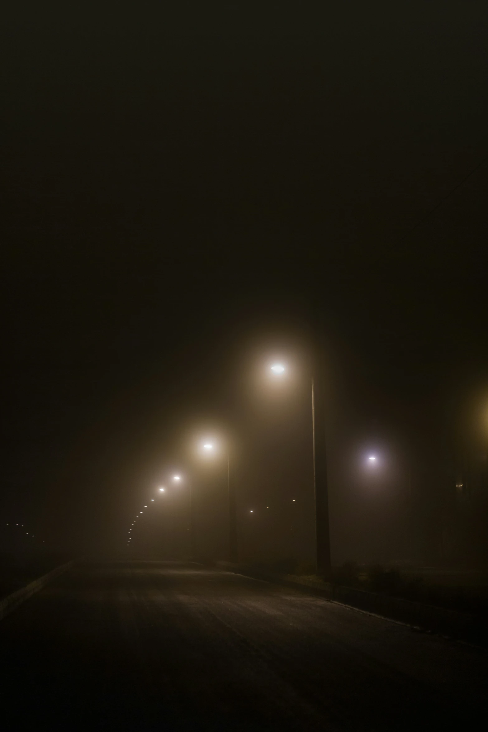 an empty road at night with street lamps on it