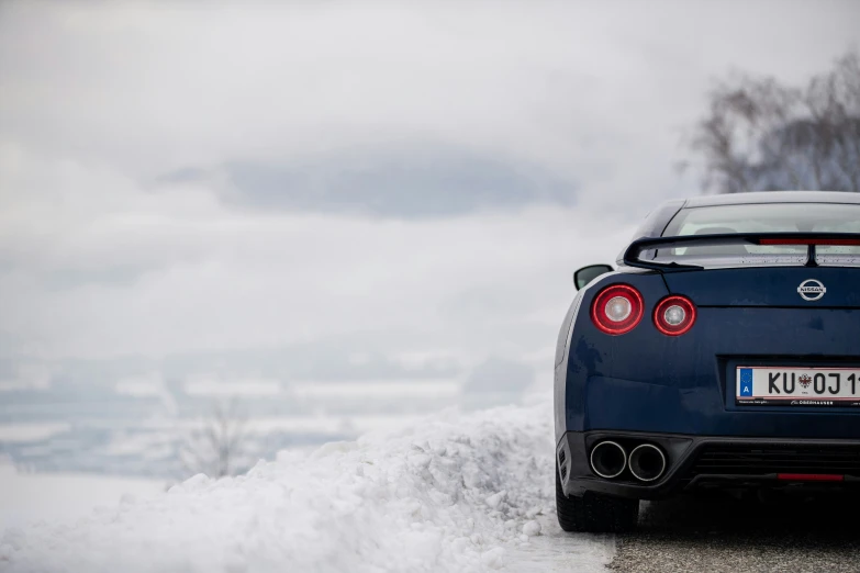 a blue sports car on road with snow and trees