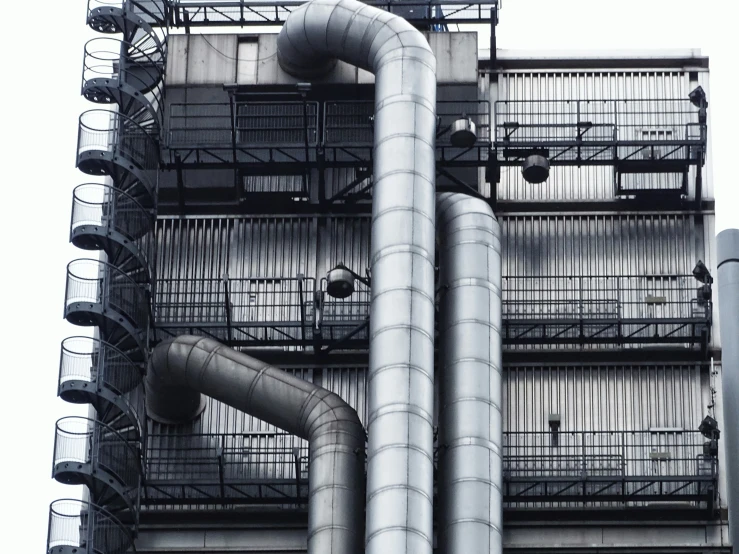 a black and white image of pipes, air ducts, and a large building